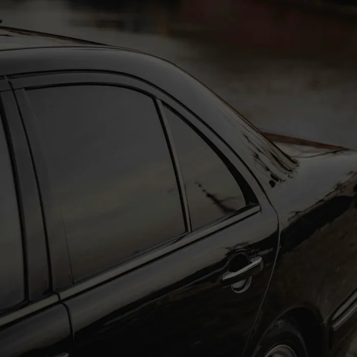Black sedan with dark ceramic window tint, side profile detail